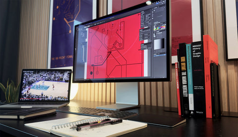 Behind-the-scenes view of X&O Prints design process: monitor editing “The Last Shot” diagram, NBA replay on laptop, design books on desk.